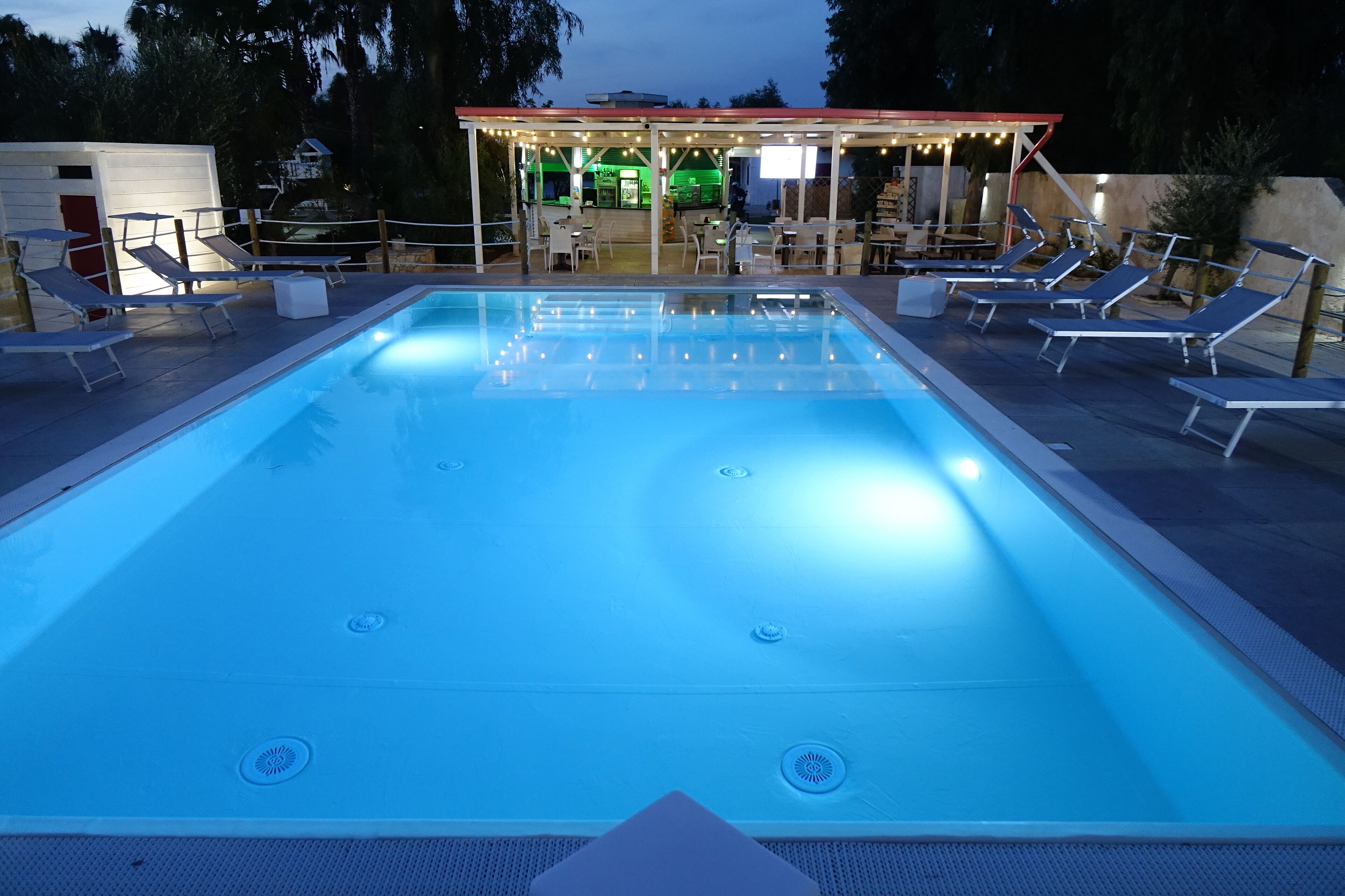 Ein Pool mit Liegestühlen und einer überdachten Sitzgelegenheit.