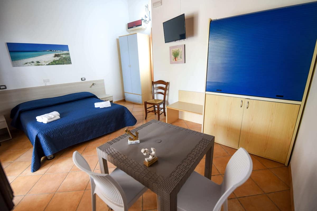 Een hotelkamer met twee bedden, een tafel, stoelen, een televisie en een kledingkast.