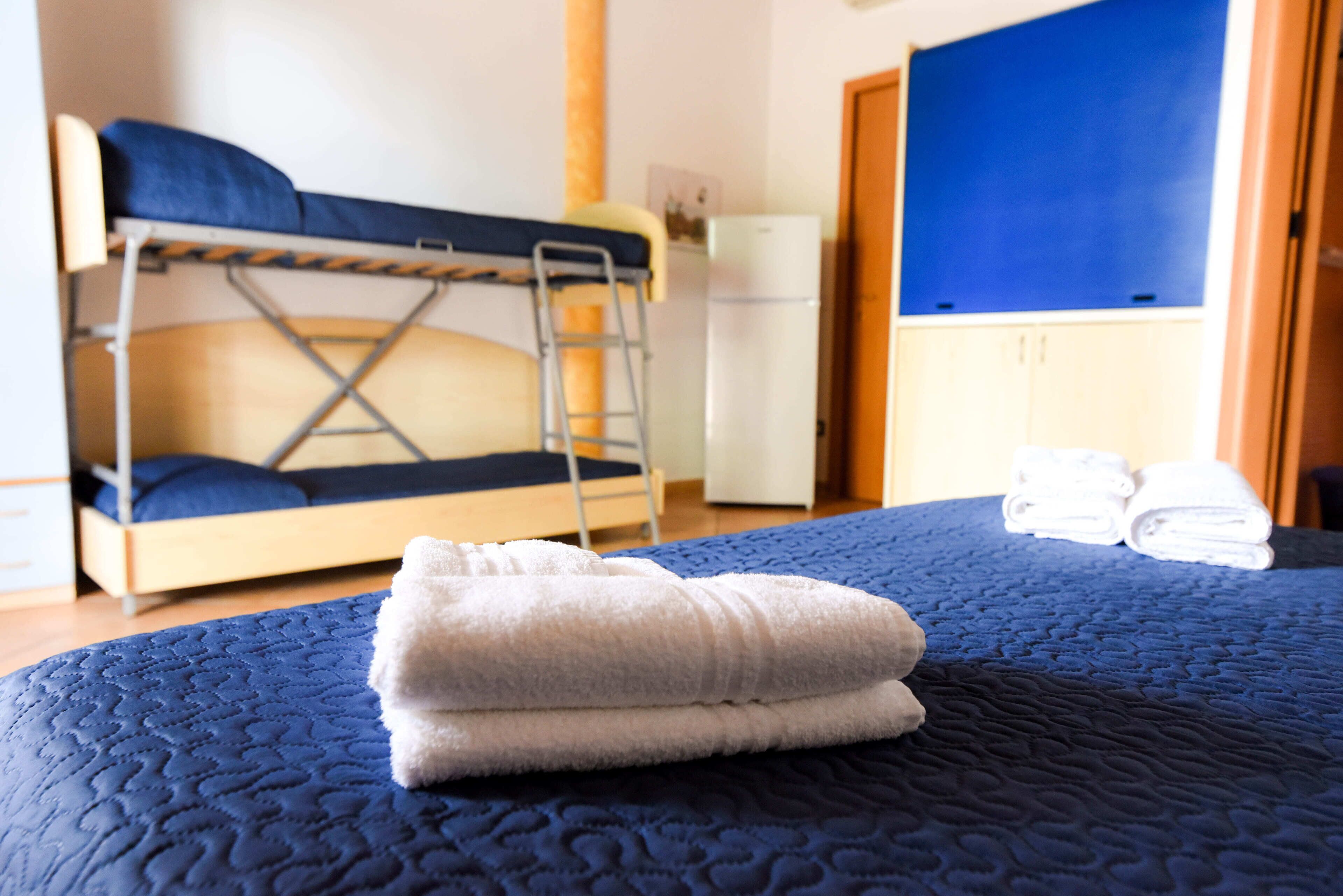 Un letto a castello con una scala, un frigorifero bianco e una parete blu.