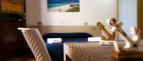 A room with a bed, a small table with decorative items, and a wall-mounted picture.