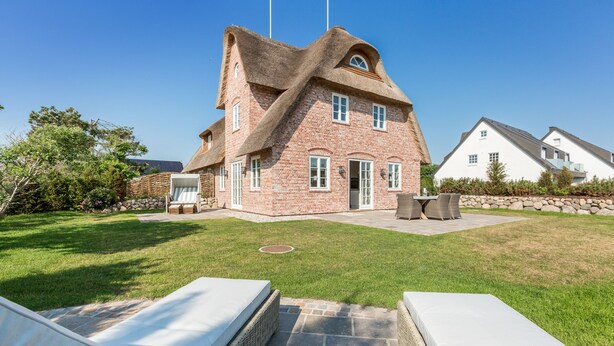 A house with a unique architectural design, featuring a sloped roof and brick construction.