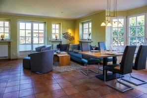 Ein Essbereich mit einem für vier Personen gedeckten Tisch, umgeben von Stühlen, einer Couch und einem Couchtisch.
