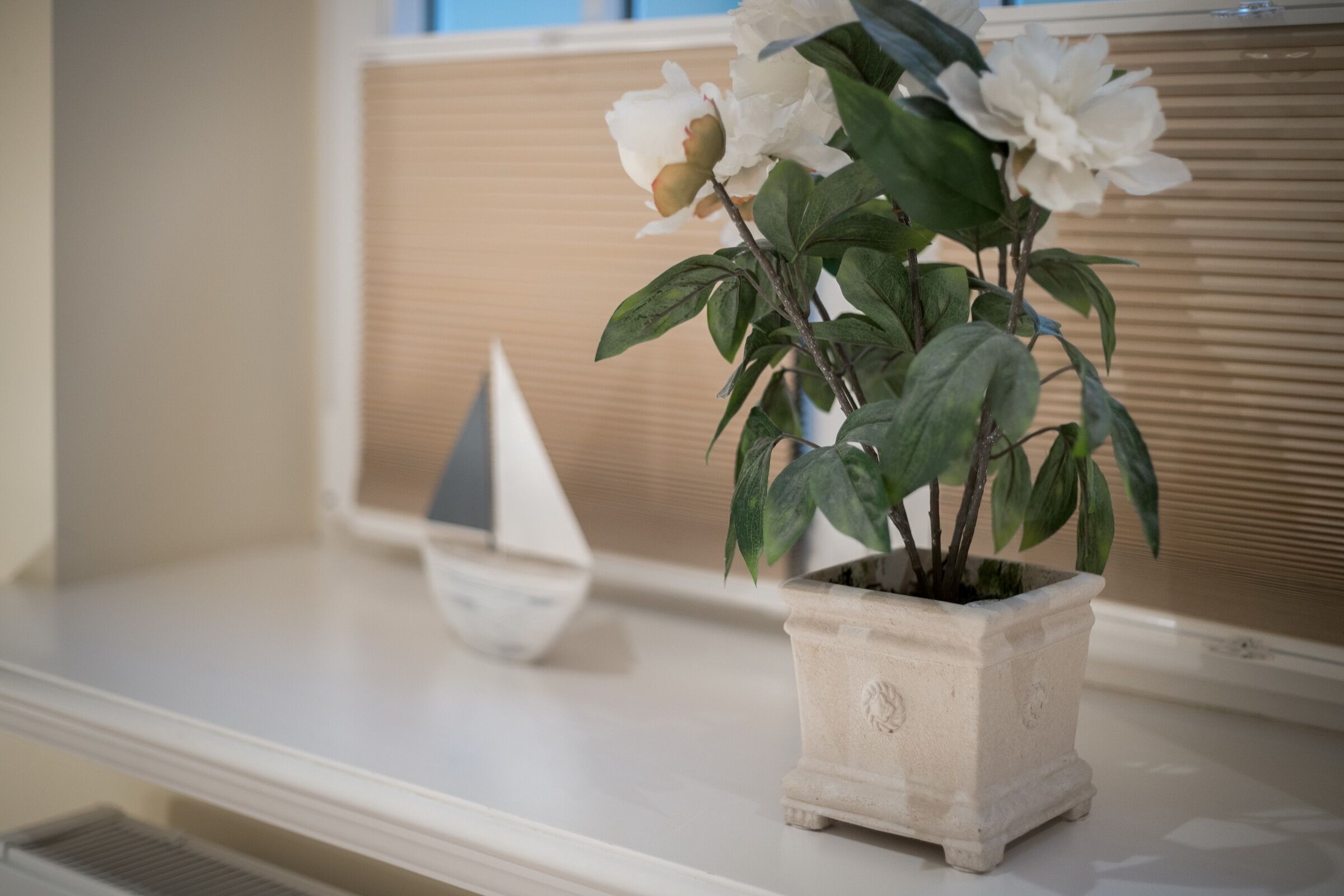 Une plante en pot, ornée de fleurs blanches, posée sur une étagère blanche.