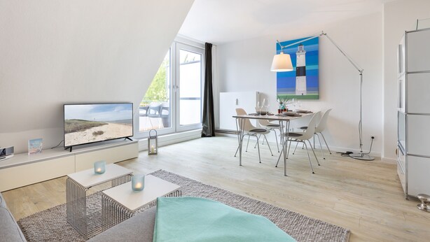 A modern living room with a TV, dining area, and artwork on the wall.