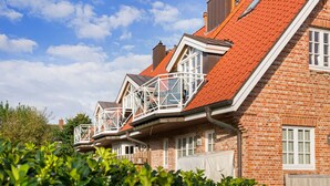 Een rij bakstenen huizen met rode dakpannen en witte raamkozijnen.