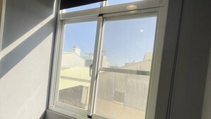 Una habitación con un ventanal grande, techo a la vista y suelo de baldosas.