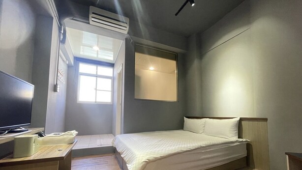 Una habitación de hotel moderna con cama, escritorio, televisor y ventana.