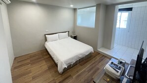 Un dormitorio con una cama, una mesita de noche, una ventana y un televisor.