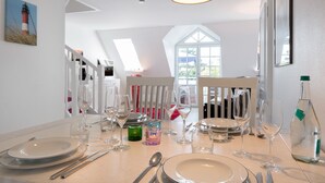 Un coin repas avec une table mise pour le repas, comprenant des assiettes, des couverts et des verres.