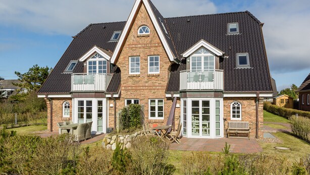A large, two-story house with a brick facade, multiple windows, and a sloped roof. - Strandnaher State-of-the-art Luxus (Wenningstedt-Braderup (Sylt))