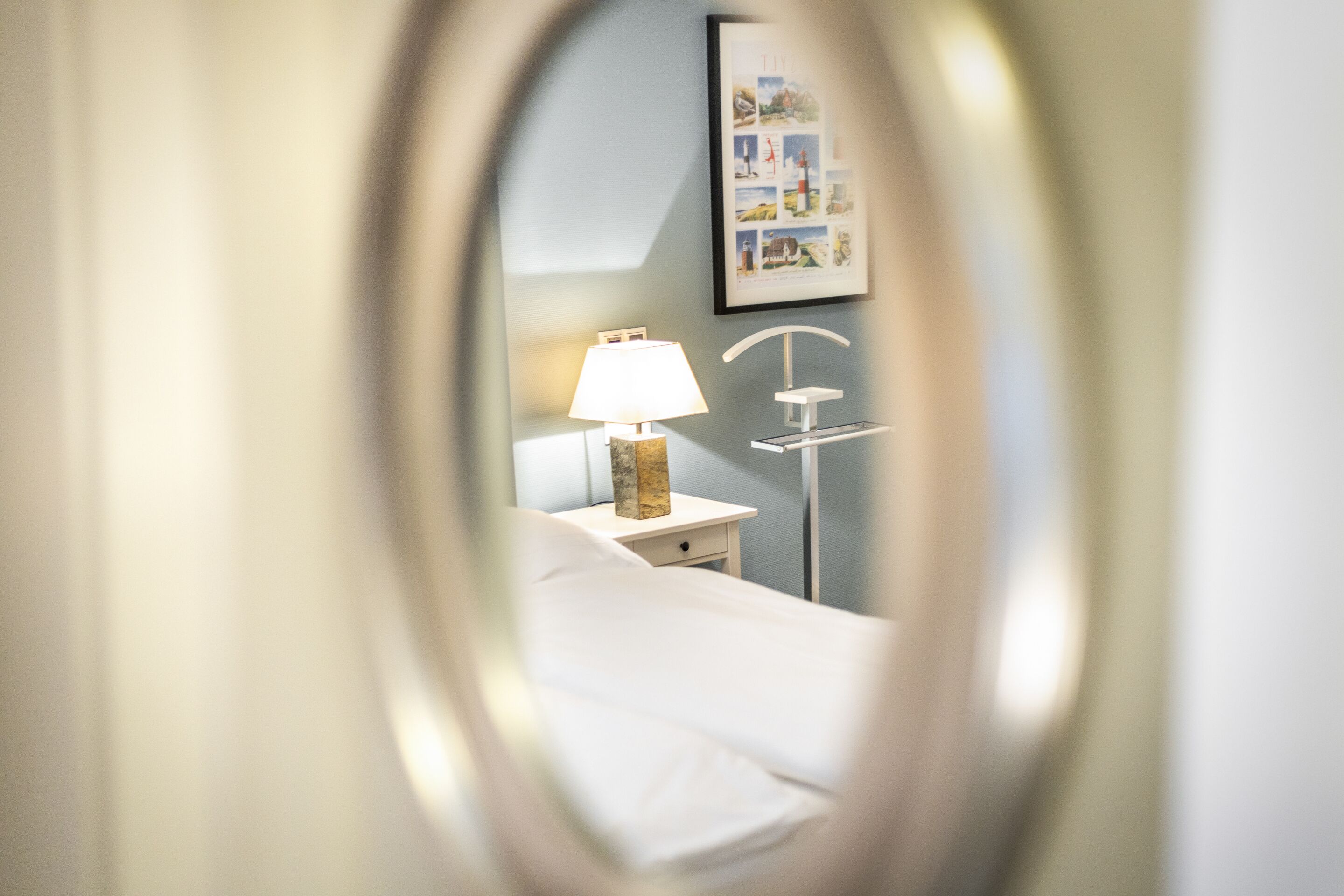 Een hotelkamer met een bed, een nachtkastje met een lamp en een lijst met een foto aan de muur.
