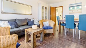 Uma sala de estar com sofá, cadeiras, uma mesa de centro e um espaço de jantar com cadeiras e mesa.