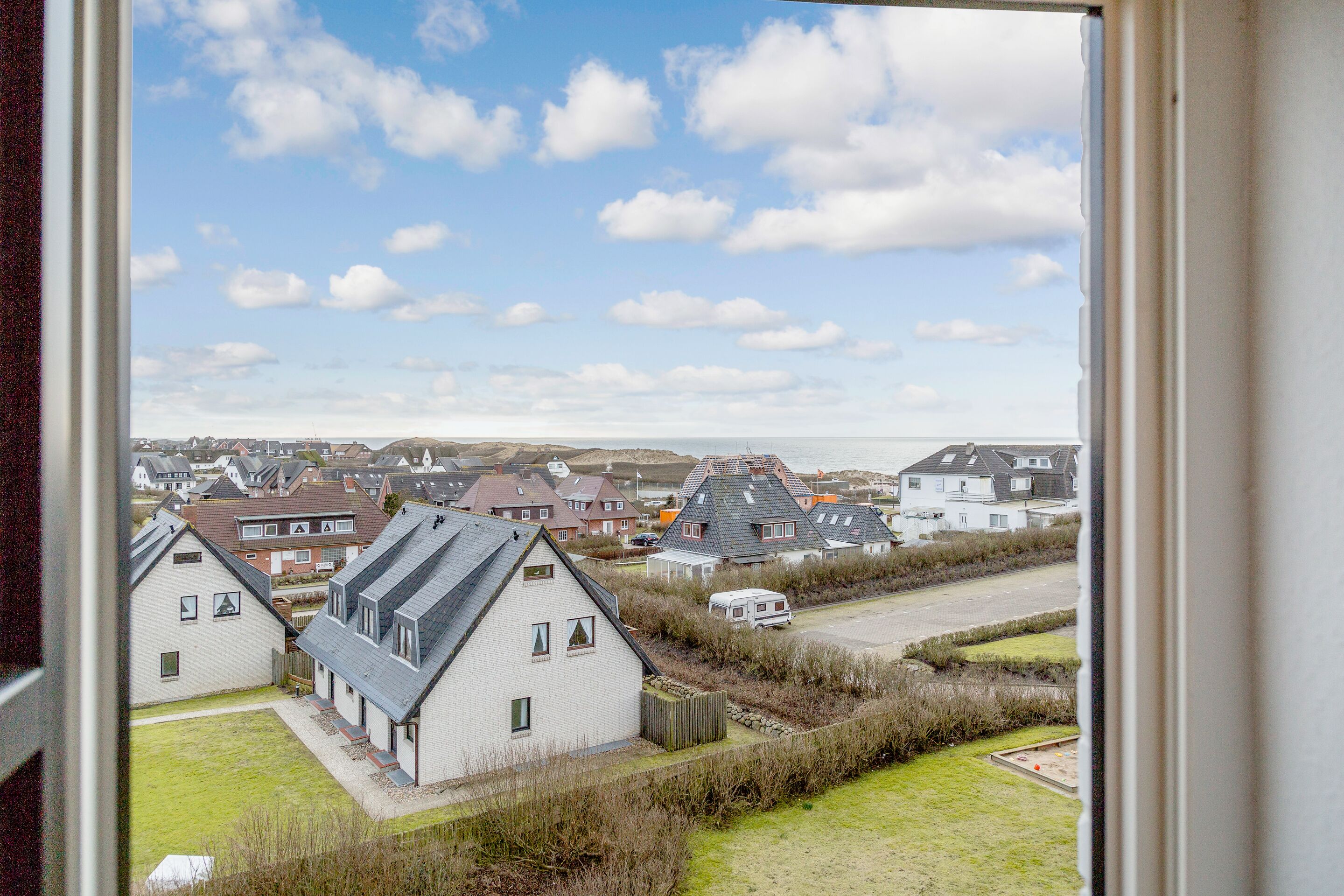 Um bairro residencial com casas, um campo gramado e um céu limpo.