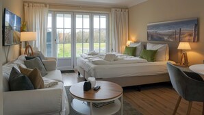 Ein Hotelzimmer mit einem Bett, zwei Nachttischen, einem Sofa, einem runden Couchtisch und einem Bild an der Wand.