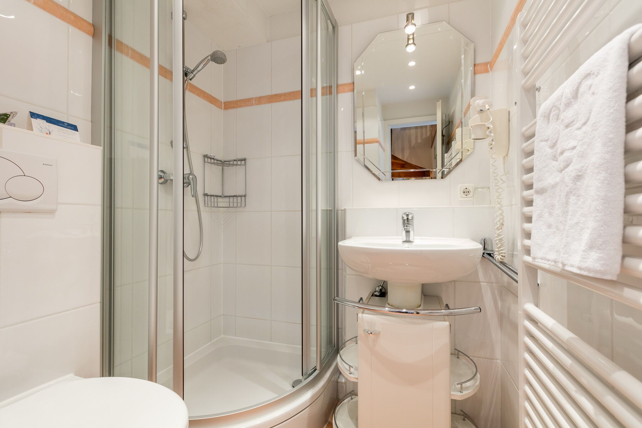 Une salle de bain moderne avec une douche à parois de verre, un lavabo blanc et des toilettes.