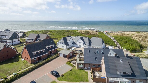 A residential area with houses, a beach, and a clear sky.