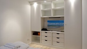 A bedroom with a bed, a TV, and built-in storage.