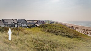 Una zona residencial costera con casas, una playa y una colina cubierta de césped.