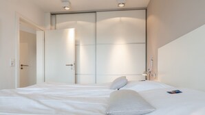 Una habitación de hotel con una cama grande, una mesita de noche y un armario.