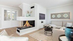 A modern living room with a fireplace, a sofa, a coffee table, and a large decorative bowl. - Düne 22 - Wohnen Unter Reet (Wenningstedt-Braderup (Sylt))