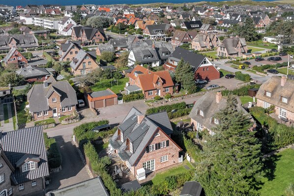 Vista aérea de un barrio residencial con casas de diferentes estilos de techo y césped cuidado.