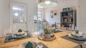 A dining area with a wooden table set for a meal, surrounded by chairs. - Appartement im Eg/ug mit ca. 76 qm Nutzfläche für bis zu 4 Personen (Wenningstedt-Braderup (Sylt))