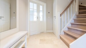A hallway with a wooden staircase, white doors, and a bench.