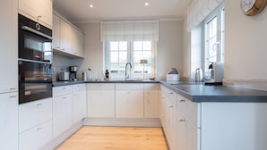 A modern kitchen with white cabinets, a black countertop, and a wooden floor.