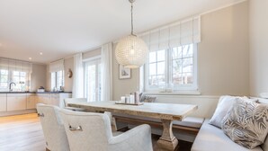 A spacious kitchen with a large dining table, two chairs, and a bench with cushions.