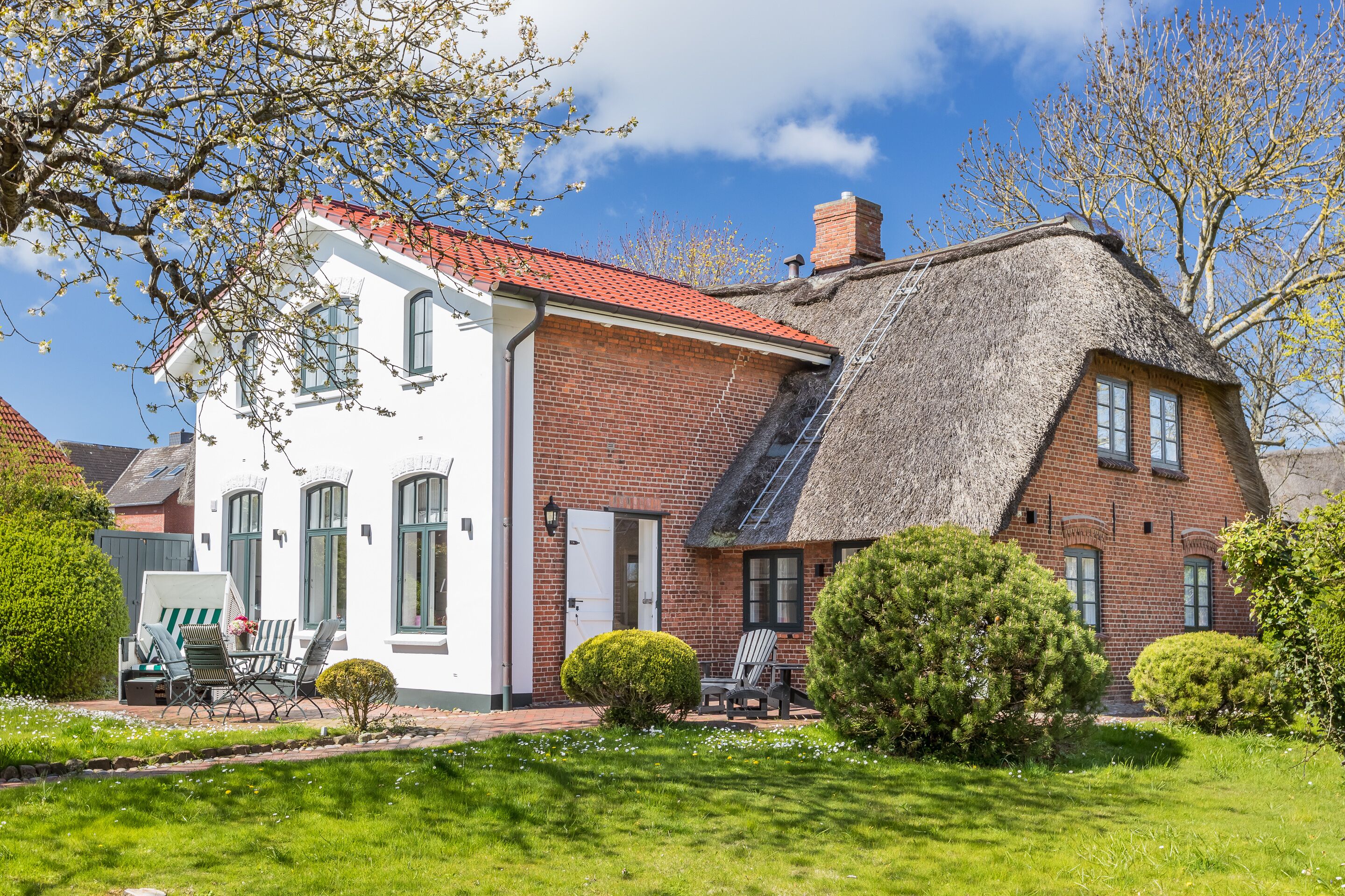 A two-story house with a red brick exterior and a thatched roof.