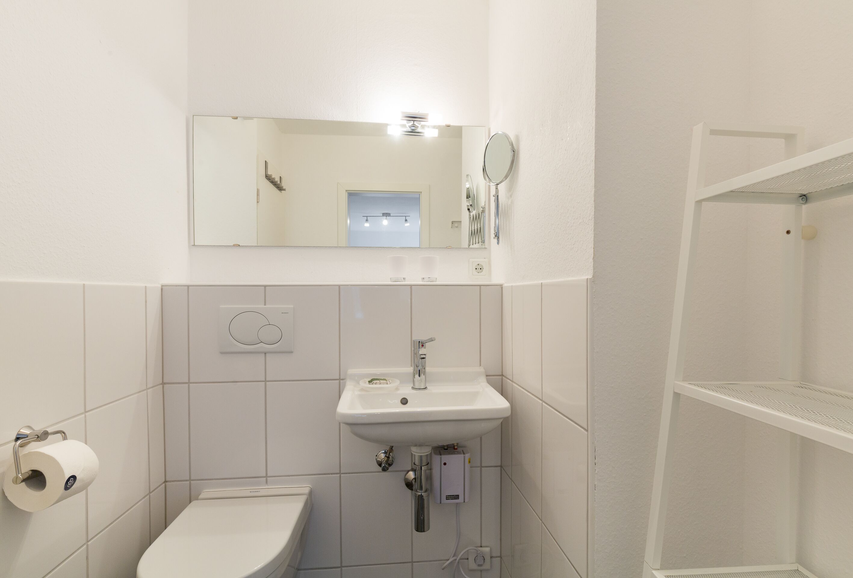 A bathroom with a white sink, mirror, and toilet.