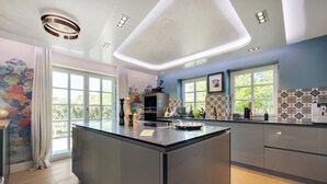 A modern kitchen with a large island, built-in appliances, and large windows. - Das Traumhaus für Designliebhaber, Ästheten, Entschleuniger und Wahre Sylfans ! (Sylt)