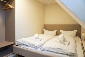A hotel room with a bed, two pillows, and a set of towels.