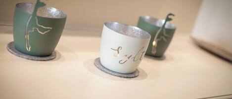 Three ceramic cups with a plant design on a shelf.