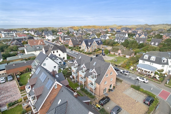 A residential area with houses, some with balconies and solar panels, and a paved road with parked cars. - Erleben Sie Einen der Beliebtesten Urlaubsorte der Insel Sylt - Wenningstedt (Wenningstedt-Braderup (Sylt))