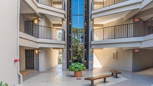 Een meerlaags atrium met een centraal glazen liftput, plantenbakken en banken.
