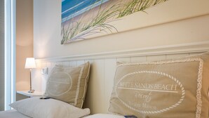 A hotel room with two beds, each with a pillow that reads "WHITE SANDS BEACH Resort Riviera Maison."