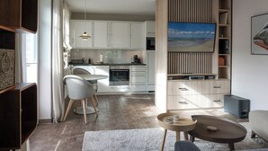 A modern kitchen with white cabinets, a dining area with a round table and chairs, and a living room with a sofa and coffee table. - Top Lage. Luxuriöse Ausstattung. Wellness im Hause (Wenningstedt-Braderup (Sylt))
