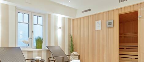 Un cuarto de spa con dos sillones de mimbre, una mesita y una puerta de sauna de madera.