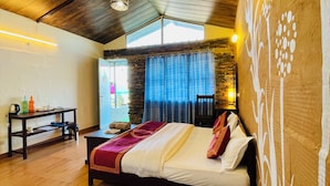 A bedroom with a bed, a nightstand, a table with a kettle, and a window with curtains. - Family in the Hills by Nature's Glamping (Kosiyakutoli)