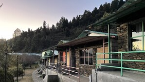 A stone building with a green roof and a small porch. - Family in the Hills by Nature's Glamping (Kosiyakutoli)