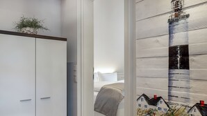 A bedroom with a bed, a wardrobe, and a wall with a painted house mural. - Top Lage. Design-ausstattung. Alles auf Einer Ebene für bis zu 2 Personen (Wenningstedt-Braderup (Sylt))