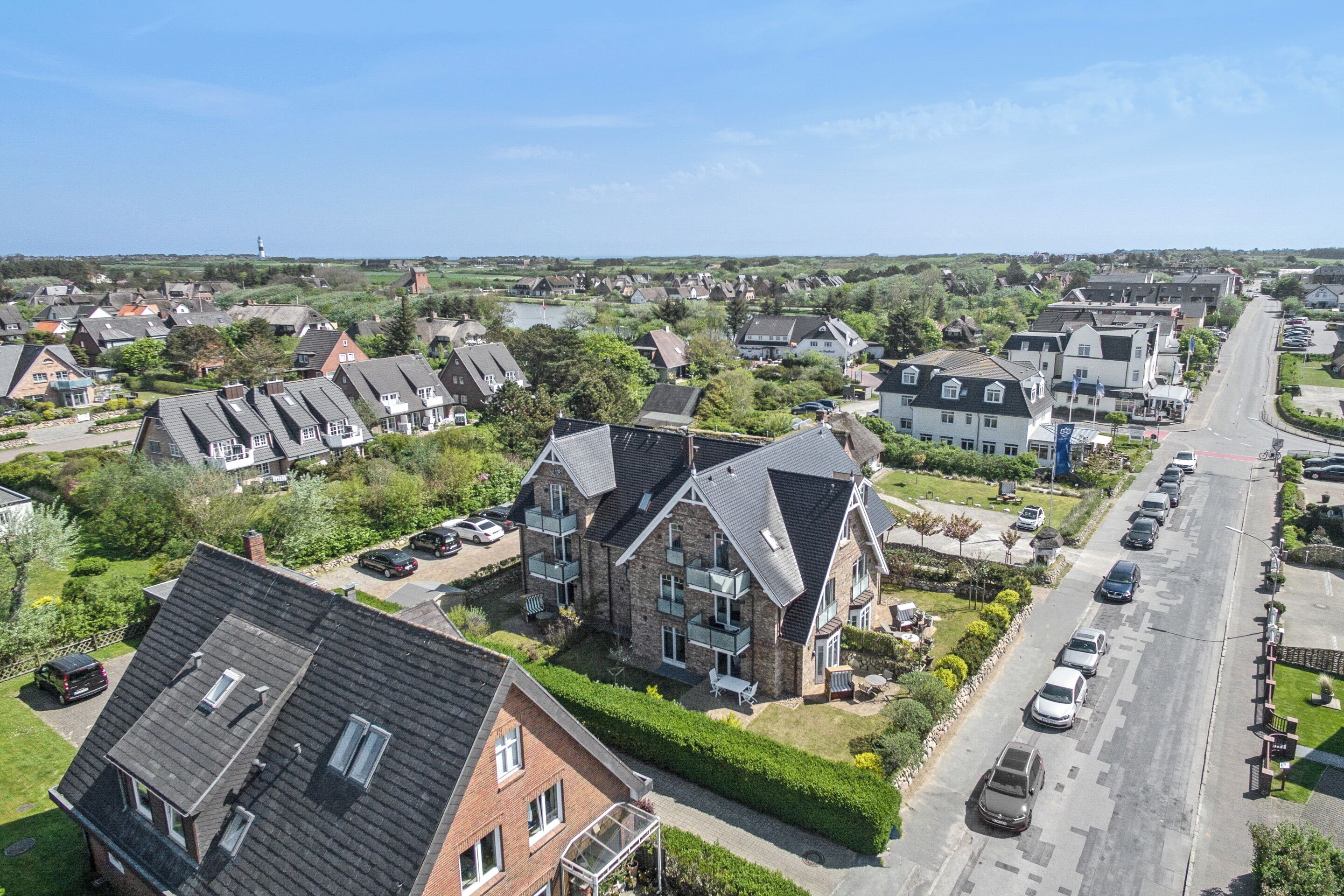 Zona residencial con casas, una avenida principal y coches aparcados.