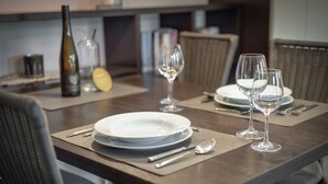 A dining table set with plates, cutlery, and wine glasses, with a bottle and glasses on the side. - Top Lage. Design-ausstattung. Alles auf Einer Ebene für bis zu 2 Personen (Wenningstedt-Braderup (Sylt))