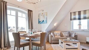 A modern living room with a dining area, a sofa, a coffee table, and a painting on the wall.