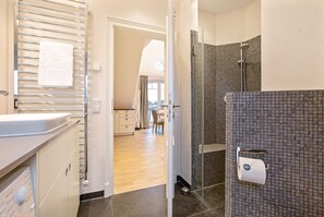 Une salle de bain moderne équipée d’une douche, d’un porte-serviettes et d’un support à papier toilette.