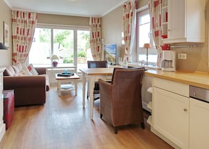 Una sala de estar acogedora con un sofá, una mesa de comedor y una zona de cocina con cafetera.
