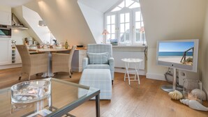 A modern loft-style living space with a kitchen, dining area, and a large window with a beach view. - Sunsets & a lot More (Wenningstedt-Braderup (Sylt))