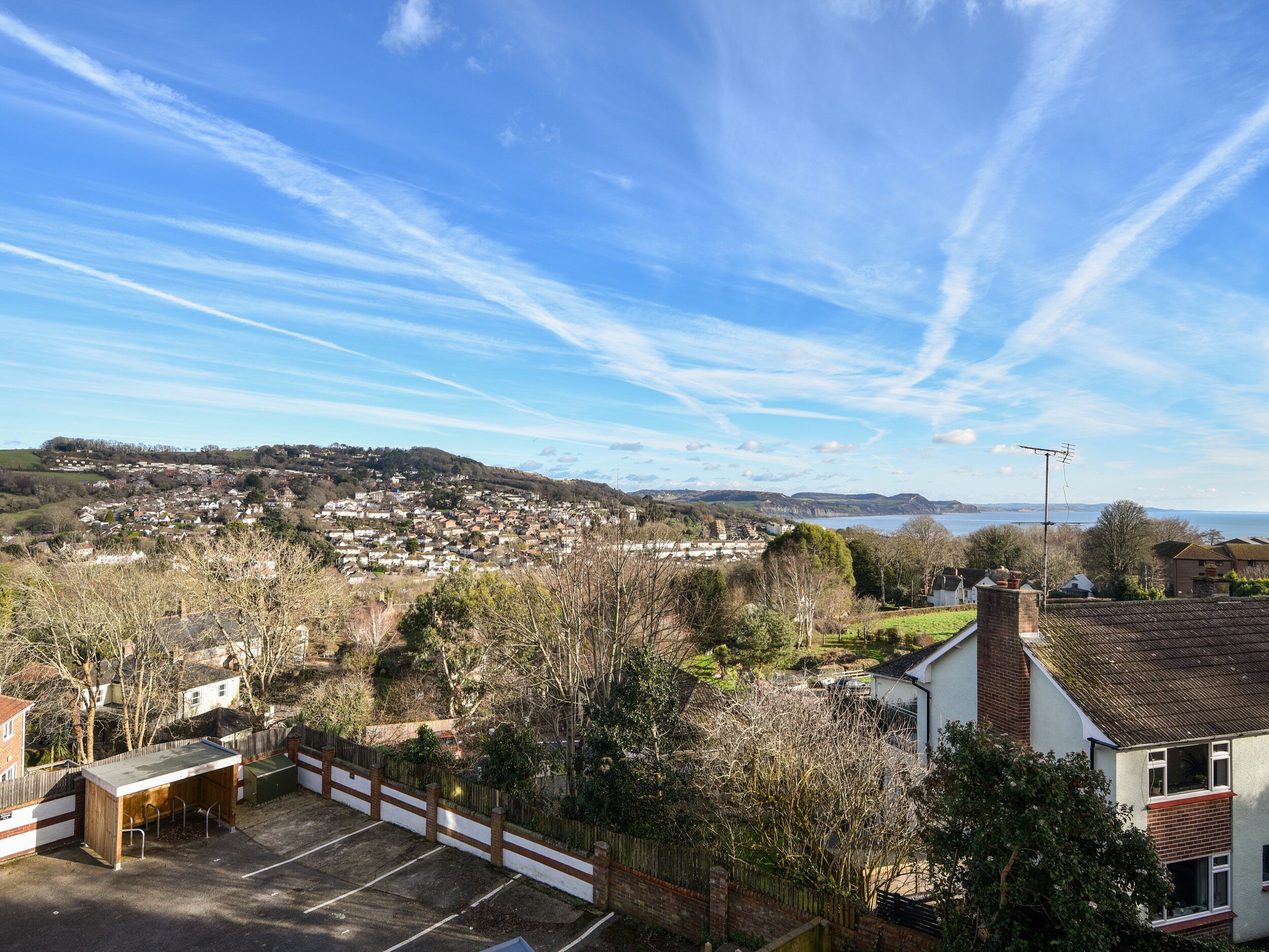 A residential area with houses, a parking lot, and a view of the sea.