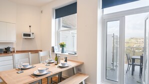 Una cucina moderna con zona pranzo, vista attraverso la porta vetrata e un piccolo balcone.